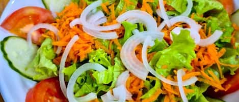A salad with lettuce, tomatoes, cucumbers, and shredded carrots.