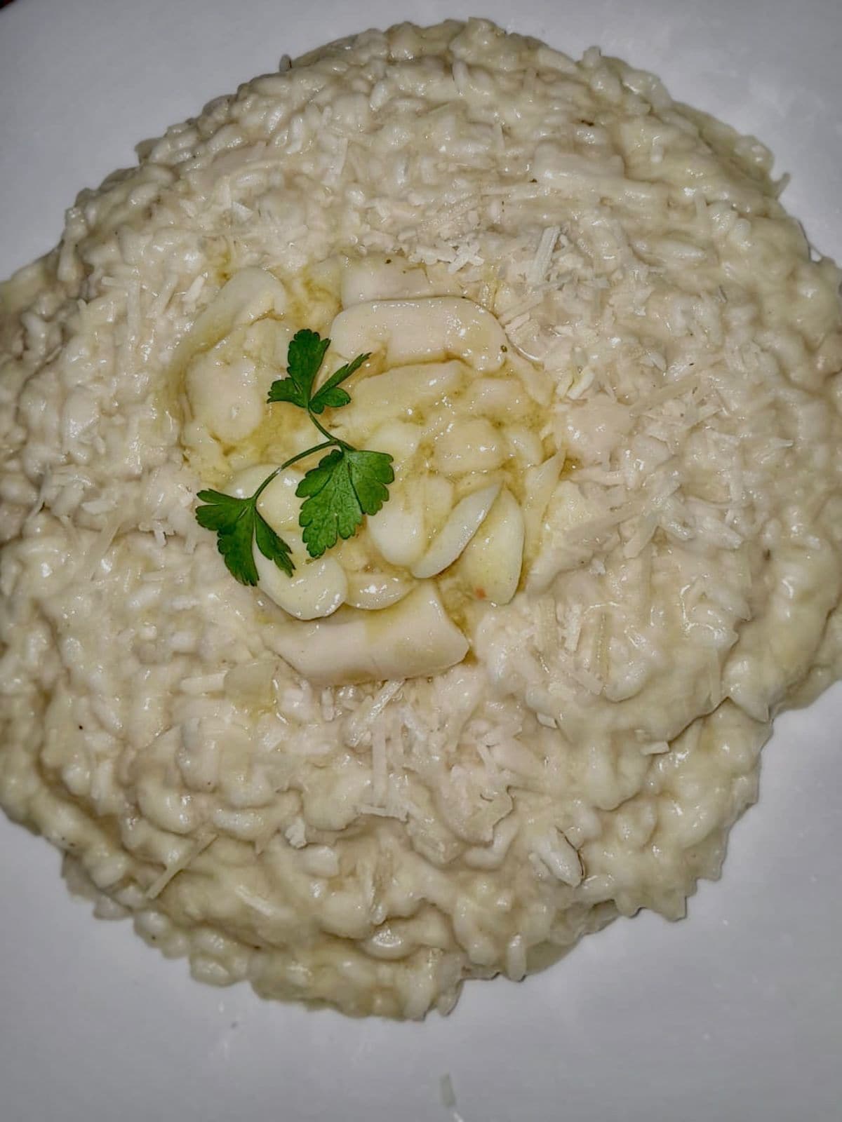 Une assiette de risotto crémeux, garnie de persil et de tranches de pomme.