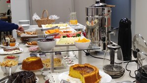 A buffet with various food items, including cakes, fruits, and pastries.