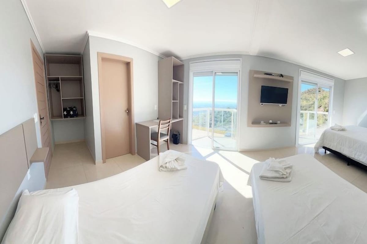 Habitación de hotel con dos camas, televisor, balcón y espacio de almacenamiento.