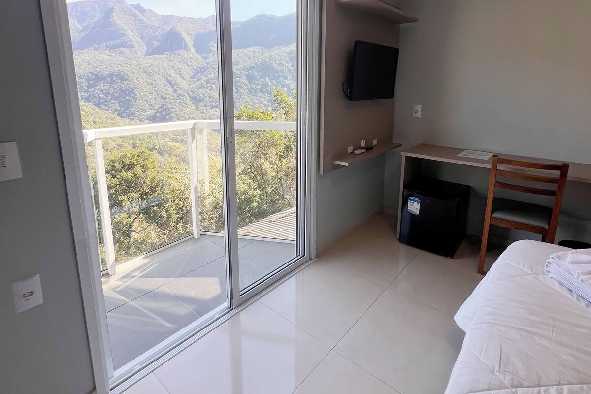 Et hotelværelse med en stor skydedør, der fører ud til en balkon med udsigt over bjergene.