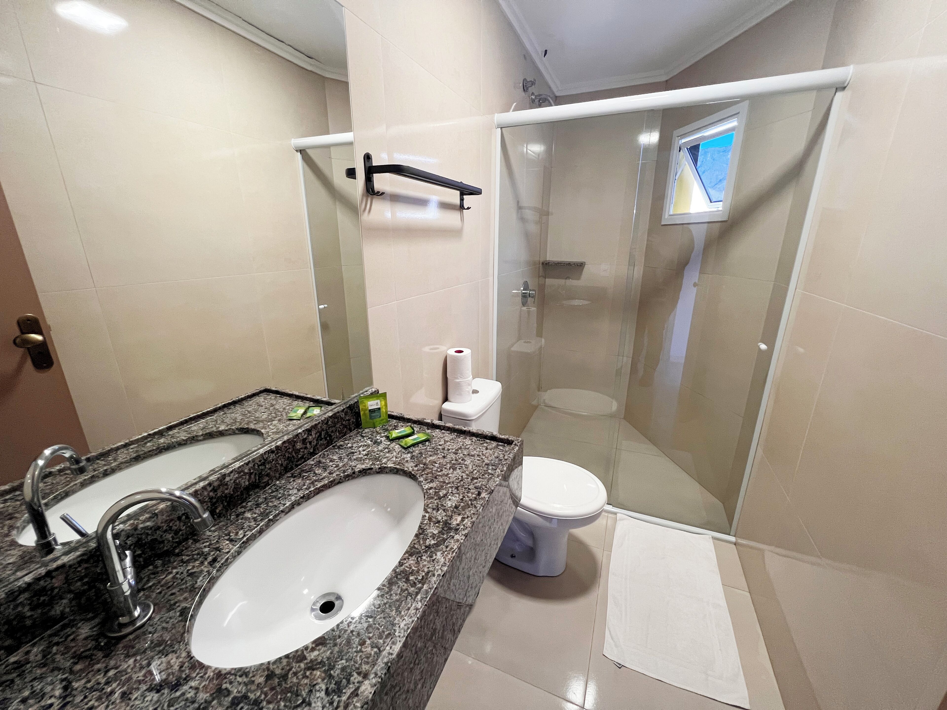 A bathroom with a granite countertop, a white sink, a toilet, and a glass-enclosed shower.