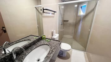 A bathroom with a granite countertop, a white sink, a toilet, and a glass-enclosed shower.