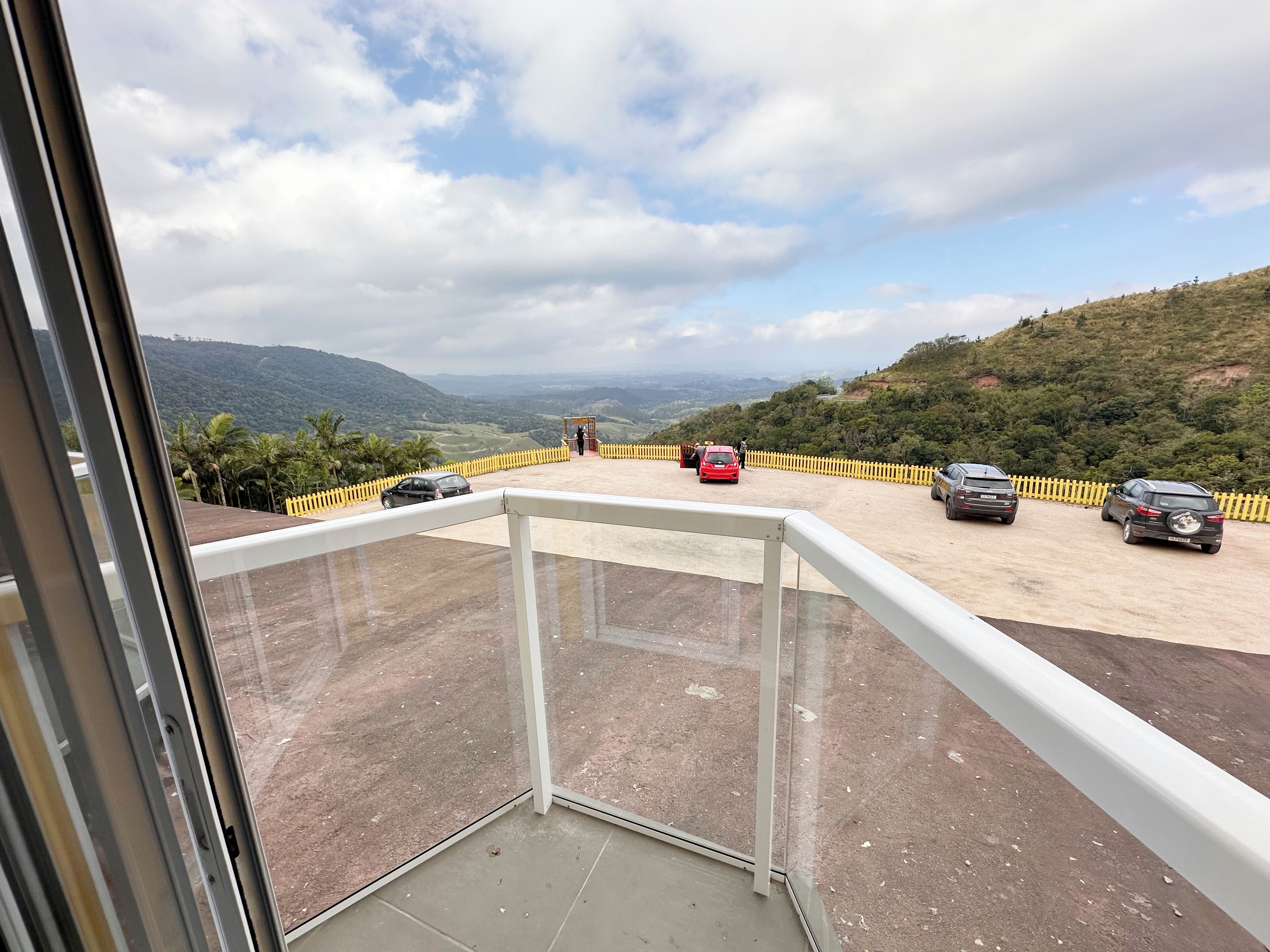 Un balcón con vistas a un estacionamiento y colinas lejanas.