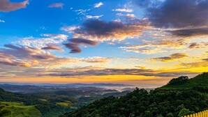 A panoramic view of a lush, green landscape with rolling hills and a clear sky.