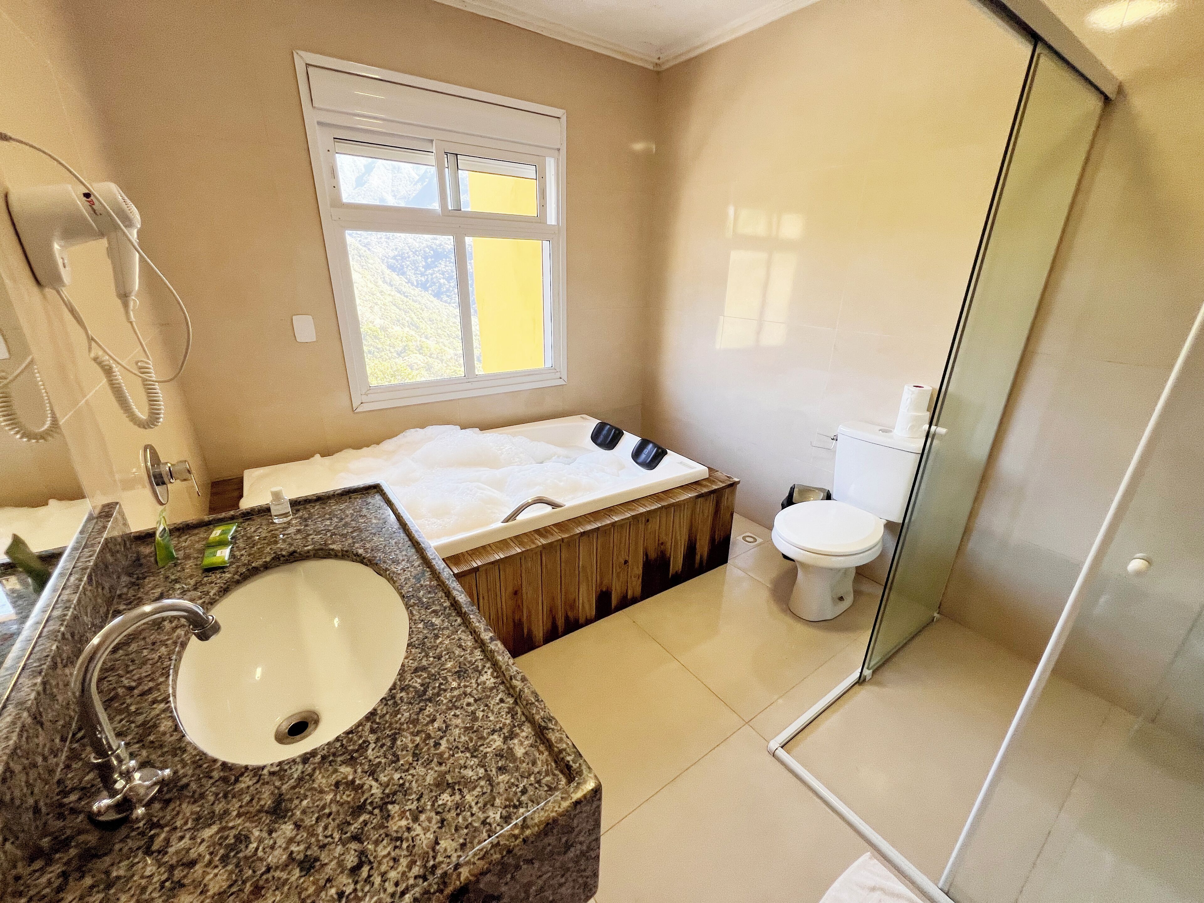 Ein Badezimmer mit Marmorwaschbecken, Badewanne, Toilette und Dusche.