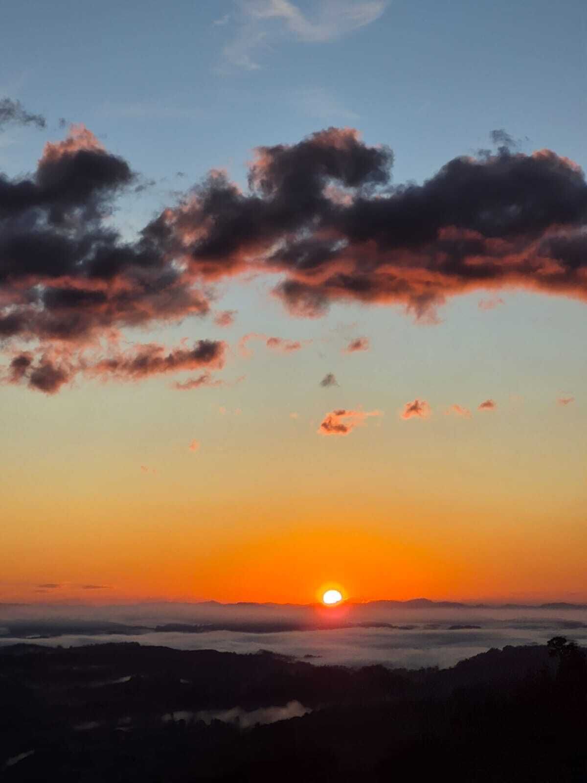 A sunset over a mountainous landscape with clouds in the sky.