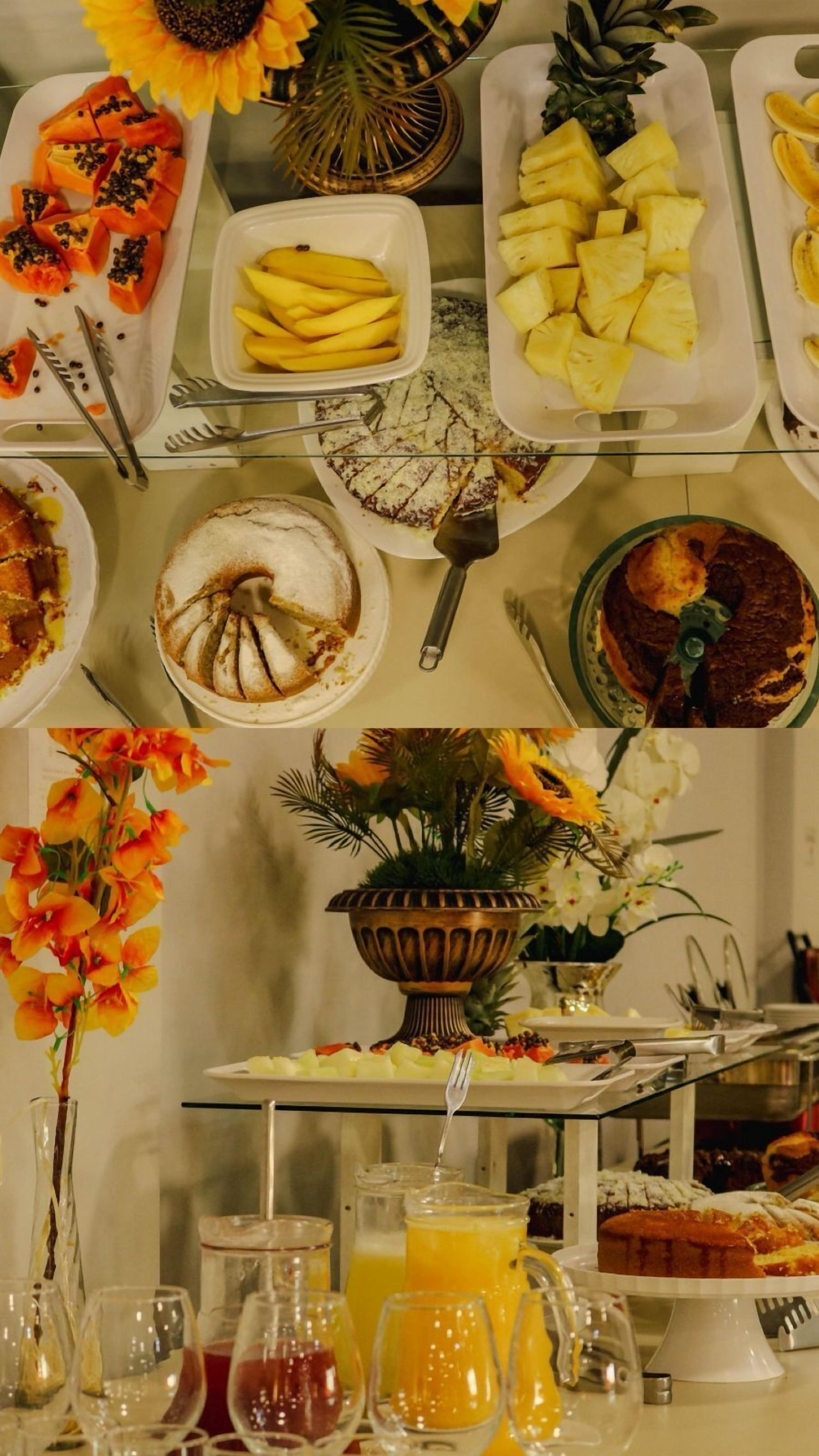 A buffet with various dishes including fruits, a cake, and a fruit punch.