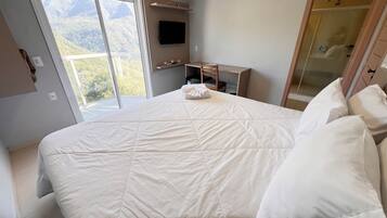 Quarto com uma cama grande, televisão, escrivaninha e guarda-roupa.