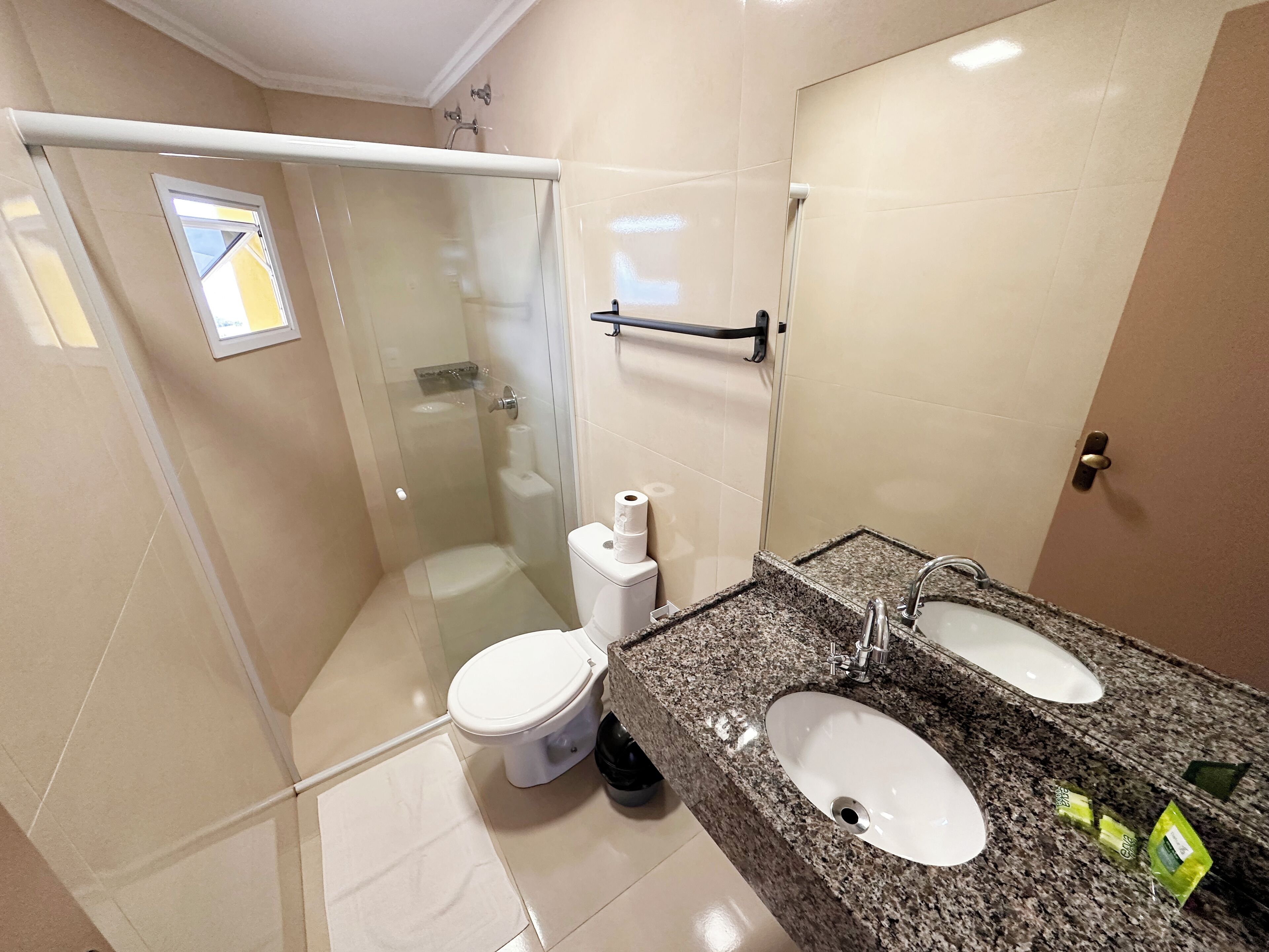 Een moderne badkamer met een douchecabine van glas, een toilet en een granieten aanrecht met twee wasbakken.