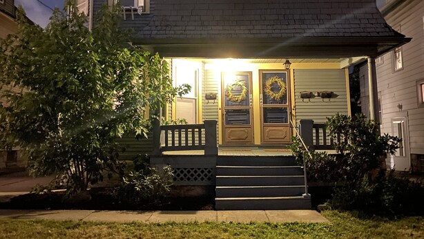 A two-story house with a front porch, steps, and a small garden area. - King Suites - 2 King Beds & Garage Parking (Lakewood)
