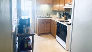 A kitchen with wooden cabinets, a white refrigerator, a stove, and a sink. - King Suites - 2 King Beds & Garage Parking (Lakewood)
