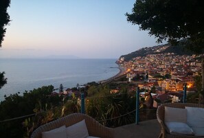 A coastal cityscape with a view of the sea and a hillside settlement.