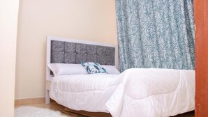 A neatly made bed with a grey headboard, white bedding, and a patterned pillow. - Stay.Plus Royale Village Apartment (Syokimau)