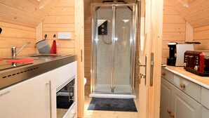 A wooden interior with a glass-enclosed shower, a sink, and a coffee machine.