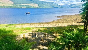 A lake with a boat, a sandy beach, and a campfire setup.
