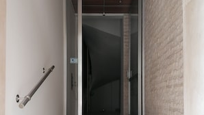 Eine Treppe führt zu einem Raum mit Holzboden und einer Ziegelwand.