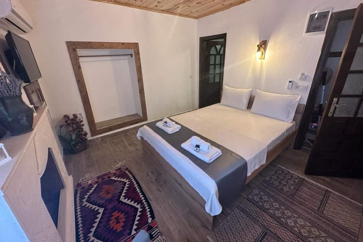 A bedroom with a bed, a bench, a wall-mounted heater, and a door.