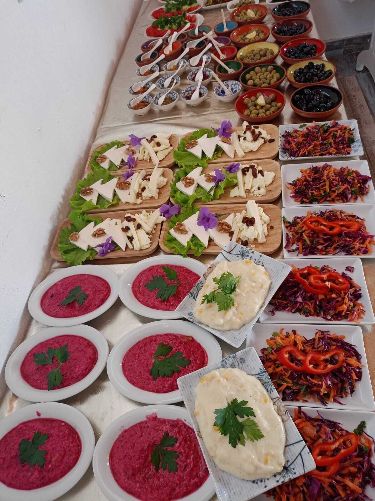 Una mesa de buffet con diversos platos, incluyendo ensaladas, salsas y bandejas de queso decoradas.