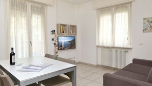 Un soggiorno moderno con tavolo da pranzo, divano e TV a parete.