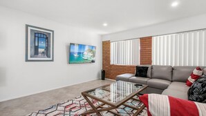 A modern living room with a grey sofa, a glass coffee table, and two paintings on the wall. - Bell Street 36, Dicky Beach (Dicky Beach)
