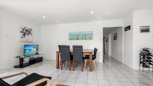 A modern living room with a dining area, a TV, and a wine rack. - Bell Street 36, Dicky Beach (Dicky Beach)