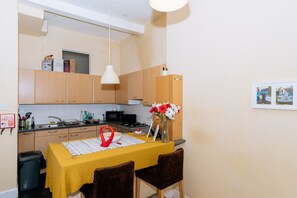 A compact kitchen with wooden cabinets, a microwave, and a dining table with a yellow tablecloth.