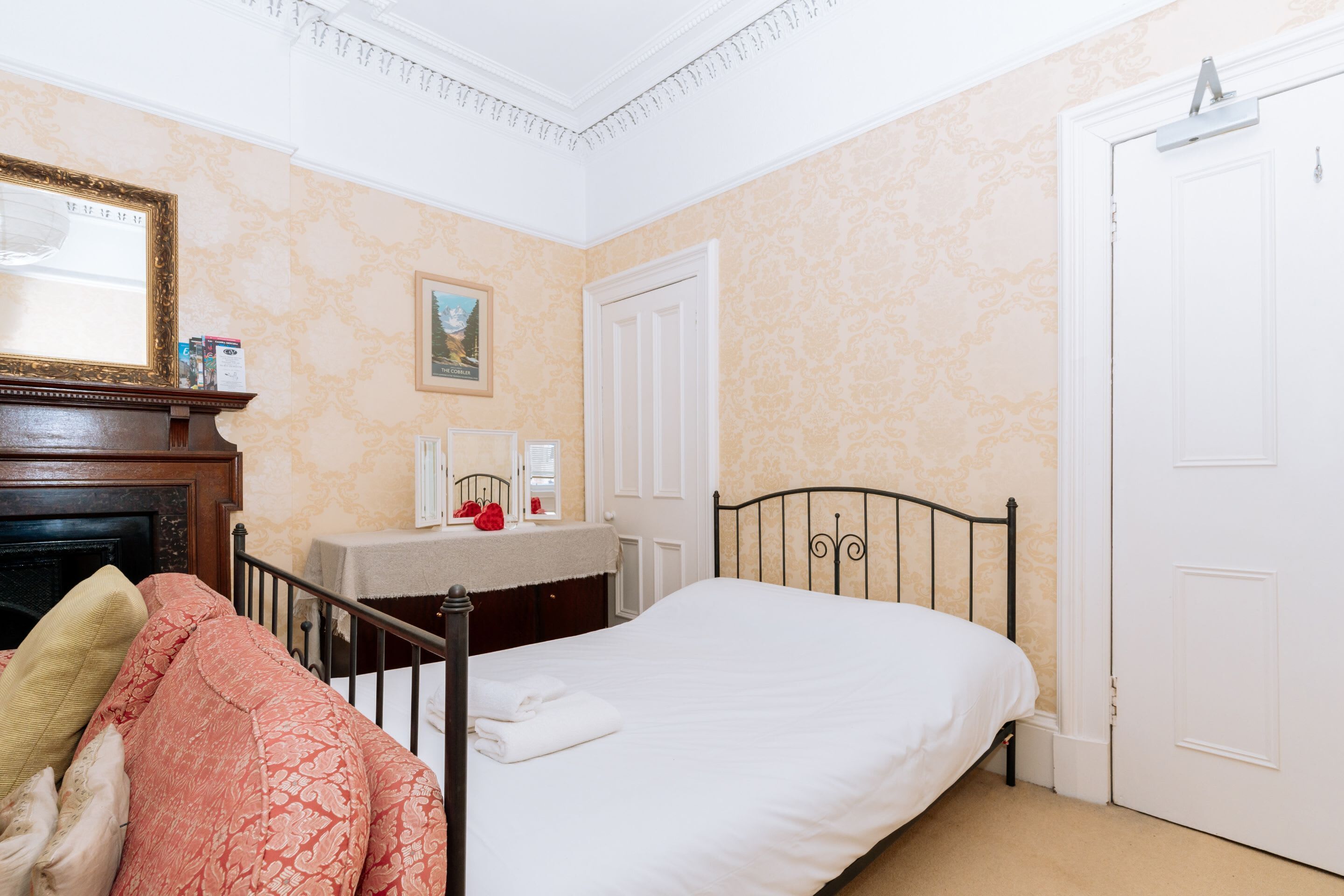 A bedroom with a bed, a dresser, a mirror, and a door.