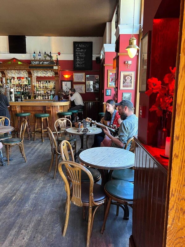 A cozy bar area with wooden furniture and a variety of bottles on shelves.