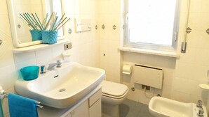 Un baño con lavamanos, inodoro, bidé y ventana.