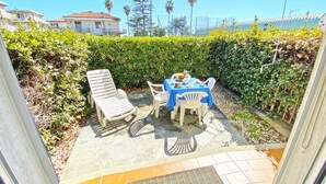 Un patio al aire libre con una mesa para dos, rodeado de follaje y vistas despejadas del entorno.