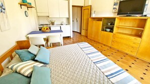 Una habitación pequeña con cama, mesitas de noche y televisor.