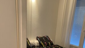 A bedroom with a bed, a window with blinds, and a door. - Appartement MTM (Montpellier)