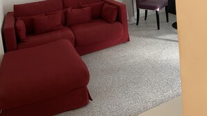 A red sofa, a purple chair, and a small table in a room with white walls and a tiled floor. - Appartement MTM (Montpellier)