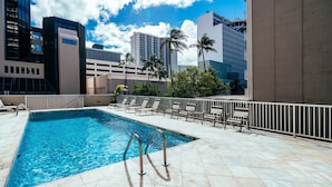 A rooftop pool with clear blue water, surrounded by lounge chairs and a railing. - Ocean & Iconic Waikiki Views from the Marine Surf by the Beach w/Full Kitchen (Honolulu)