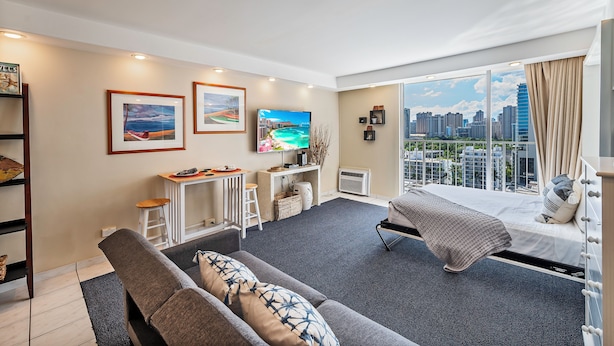 A modern living room with a sofa, a TV, and artwork on the walls. - Ocean & Iconic Waikiki Views from the Marine Surf by the Beach w/Full Kitchen (Honolulu)