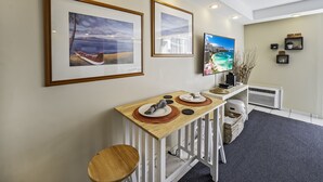 A hotel reception area with a wooden reception desk, framed artwork on the wall, a television, and a small plant display. - Ocean & Iconic Waikiki Views from the Marine Surf by the Beach w/Full Kitchen (Honolulu)