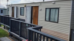 A row of mobile homes with a balcony and a small garden area.