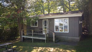 A small cabin with a porch, a bench, and a picnic table. - Rustic Muskoka Cabin on the Lake- Port Severn (Port Severn Road)