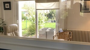 Una habitación con un ventanal grande, una silla, una mesa y un radiador.
