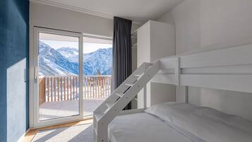 A bedroom with a bunk bed, a sliding glass door leading to a balcony with a mountain view.