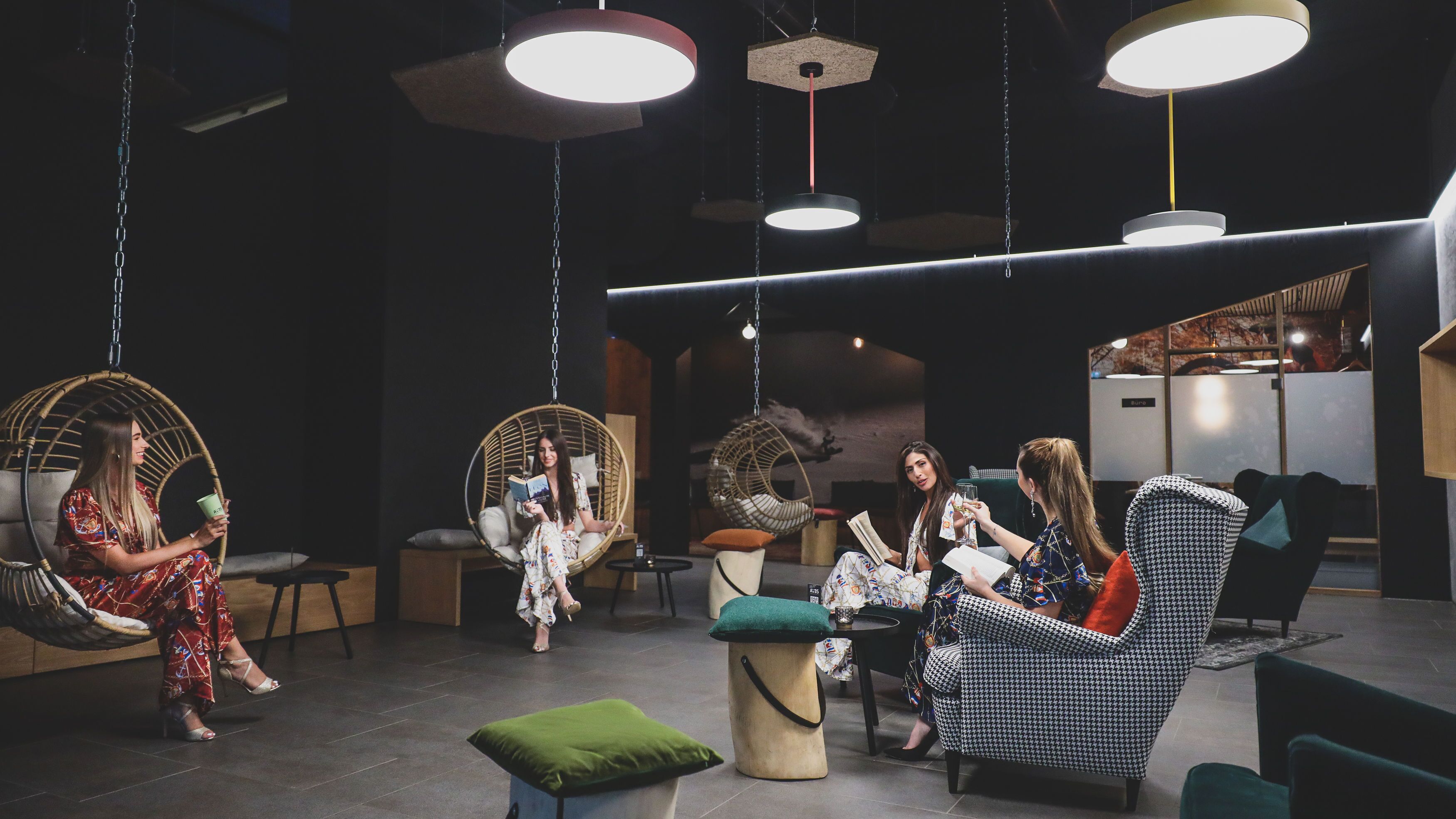Un espacio lounge moderno con sillones colgantes, una mesa de centro y un sofá.