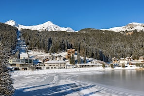 A snow-covered mountain with a ski resort, including buildings and a frozen lake.