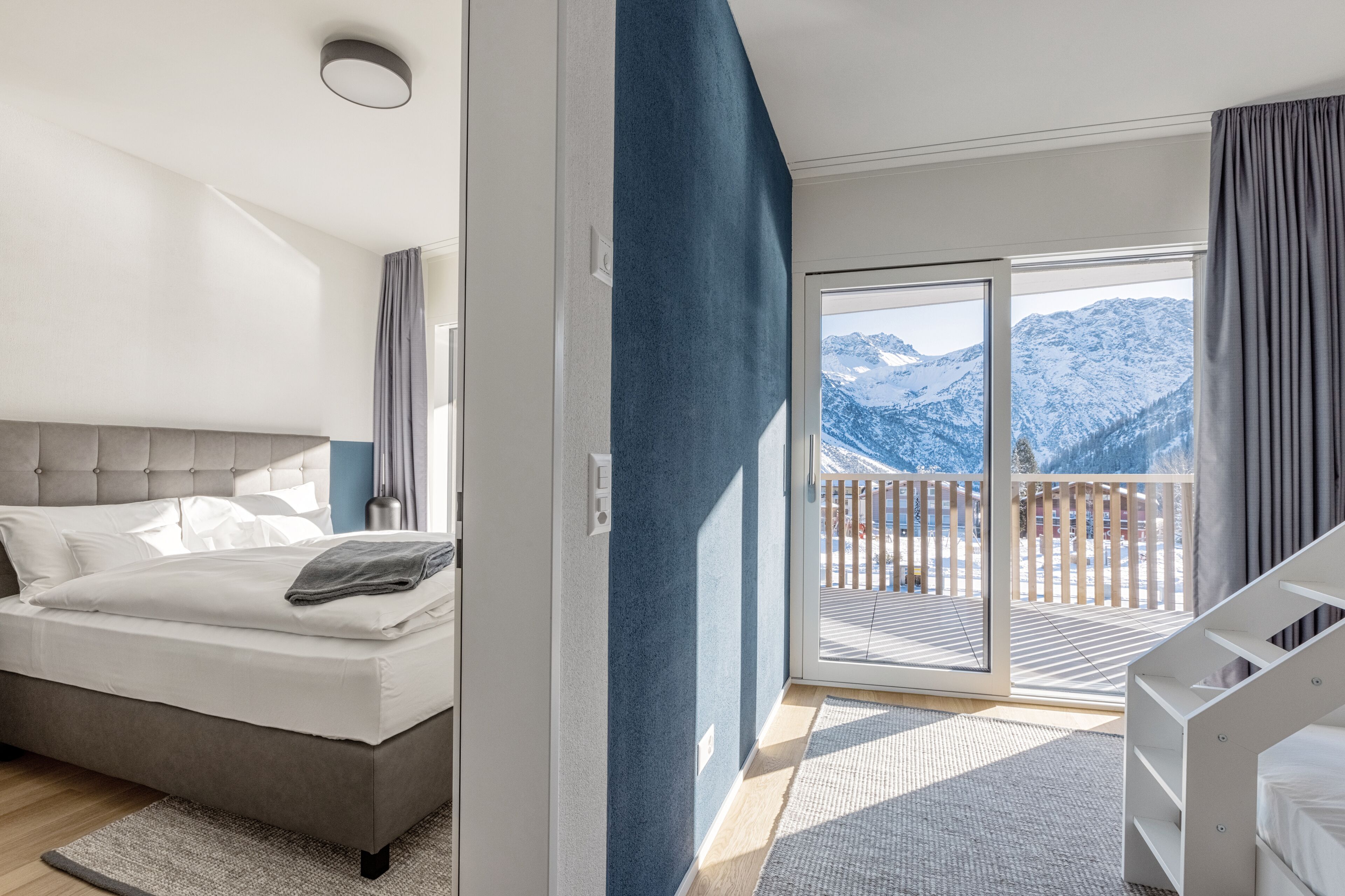 Un dormitorio con cama, vistas a montañas desde un balcón y una escalera.