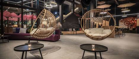 A modern interior with hanging chairs, round tables, and a purple sofa.