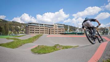 A person riding a bicycle on a curved track with a building in the background.