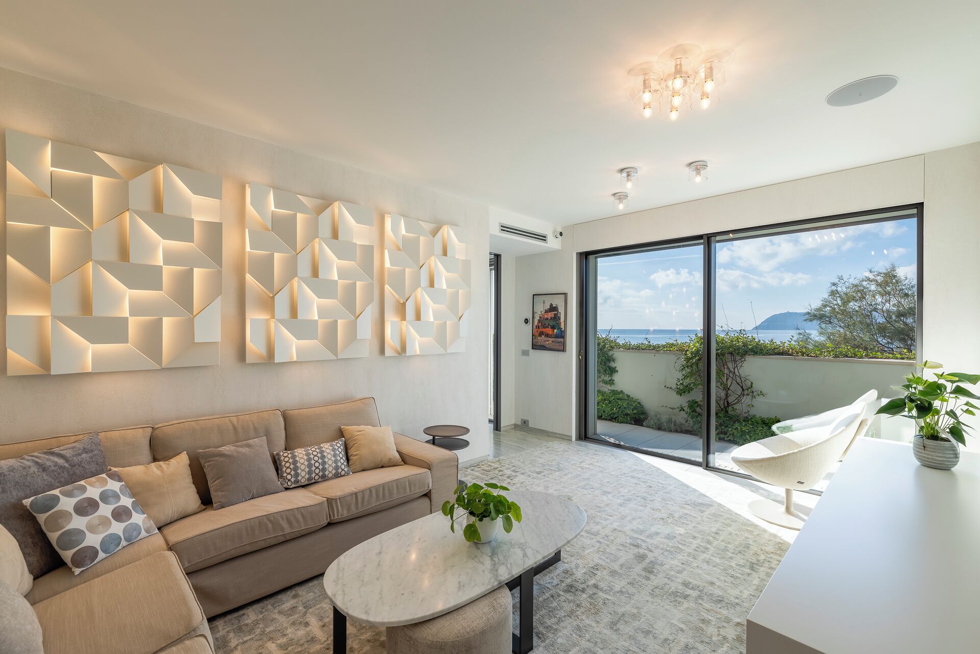 Un salon moderne avec un canapé beige, une table basse en marbre et une œuvre d’art murale aux motifs géométriques.