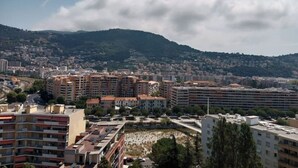 A cityscape with a mix of residential and commercial buildings, a prominent hill in the background, and a clear sky. - T2 a Proche Plage et Centre vu mer et Montagne (Nice)