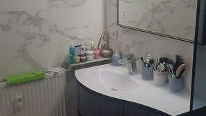 A bathroom with a white marble backsplash, a black vanity, a white sink, and a large mirror. - T2 a Proche Plage et Centre vu mer et Montagne (Nice)