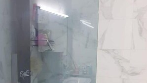 A bathroom with a glass shower enclosure, a white sink, and a marble-tiled wall. - T2 a Proche Plage et Centre vu mer et Montagne (Nice)